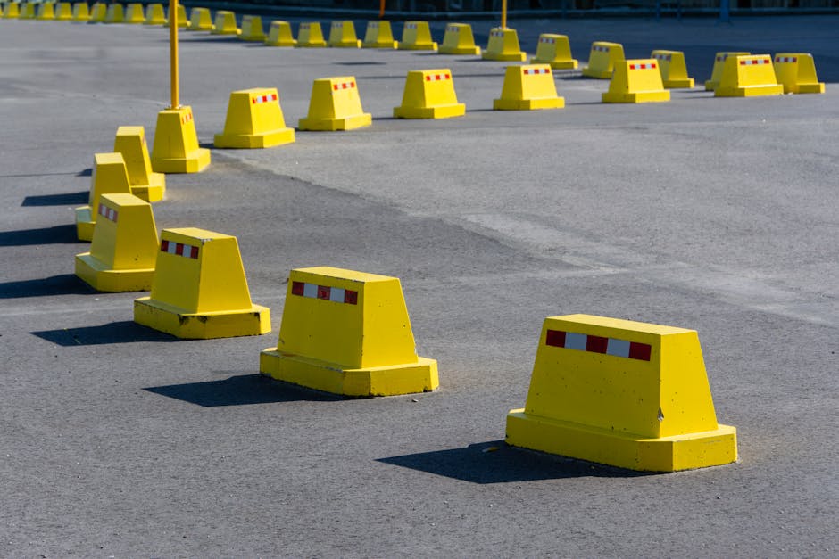 A row of bright yellow traffic barricades on a sunny asphalt road.