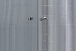 Corrugated metal wall with two mounted security cameras in a minimalist style.