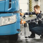 Safety-Aligned Optimal Transport in Geoengineering A male mechanic is aligning truck tires in a professional workshop setting.