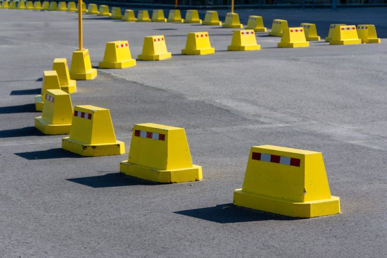 A row of bright yellow traffic barricades on a sunny asphalt road.