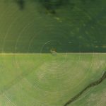 Scalable Precision Agriculture: Benchmarking Edge & IoT Aerial view showcasing farming irrigation circles and a river beside green fields.