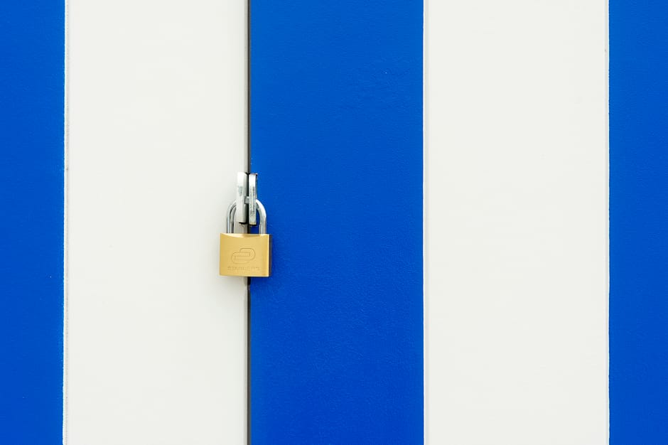 Padlock securing a blue and white striped door, symbolizing safety.