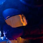 <h1>Securing the Final Frontier: Continual-Learning Decentralized Identity for Space Systems</h1> Close-up of an astronaut holding a helmet, enveloped in a dim, colorful light.