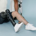 Close-up of a person wearing a bionic prosthetic leg while sitting in a studio setting.