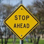 Vibrant yellow stop ahead sign in an outdoor park setting in Dallas, Texas.