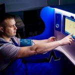 A man uses a touch screen for a telemedicine health check in a modern setting.