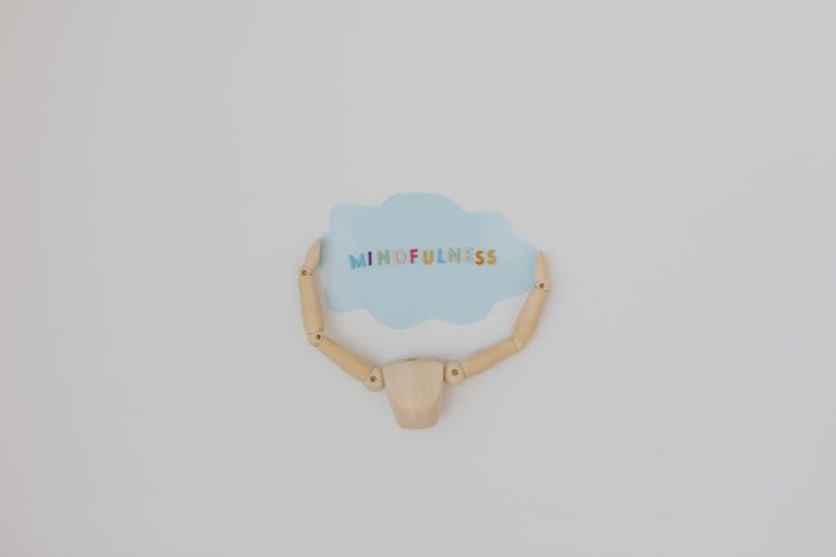 Minimalist image of a wooden figure holding a speech bubble saying 'Mindfulness'.