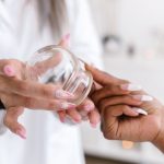 Close-up view of hands handling a glass cup for cupping therapy, an alternative treatment method.