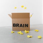 Sim-to-Real Neurosymbolic Reasoning in Nanotechnology Crumpled yellow paper pieces on floor near carton box with Brain title on white background