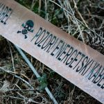 Caution tape reading 'POZOR! ENERGETSKI KABEL' lies on vegetation.