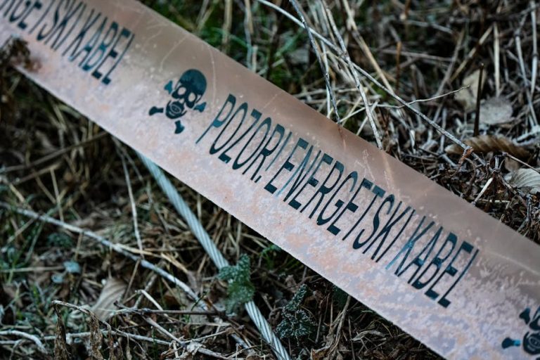 Caution tape reading 'POZOR! ENERGETSKI KABEL' lies on vegetation.