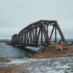 Symbol-Grounded Metamaterials: Bridging Semantics and Nano Tech Scenic view of snowy shore against ridges and rippled ocean with aged bridge in wintertime