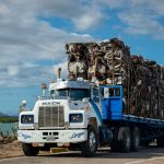 Symbol-Grounded Optimal Transport in Nanotechnology A Mack truck loaded with scrap metal travels on a rural road under a cloudy sky.