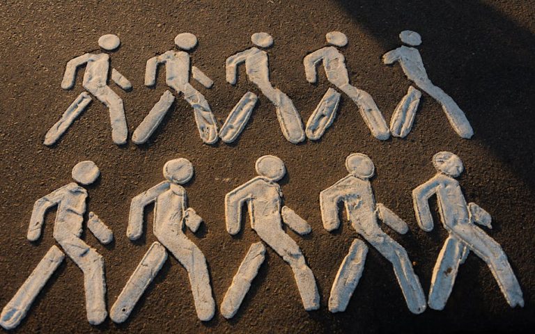 Creative chalk drawings of pedestrian figures on an urban pavement.