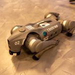 <h1>Symbol-Grounded Soft Robotics: The Future of Nanoscale Interaction</h1> A Unitree robot dog resting on an indoor concrete floor.