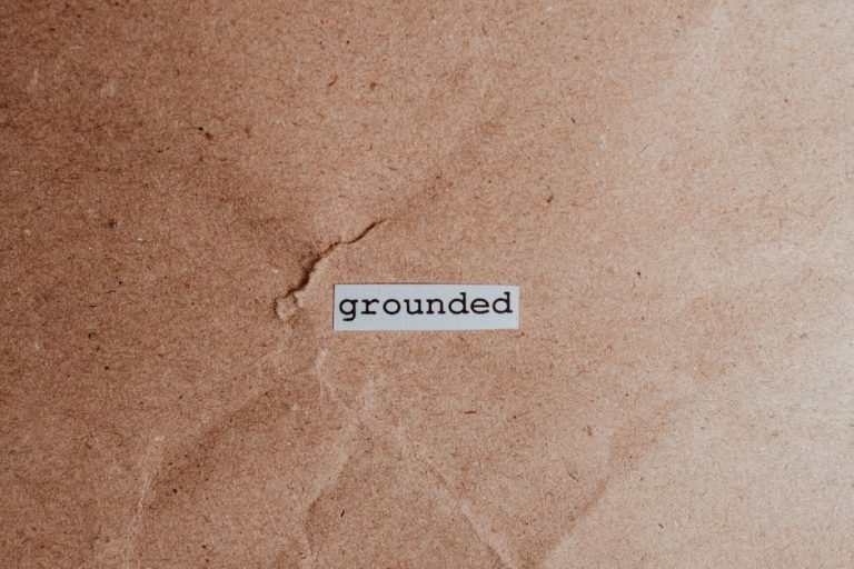 Textured brown surface with the word 'grounded', conveying stability and mindfulness.