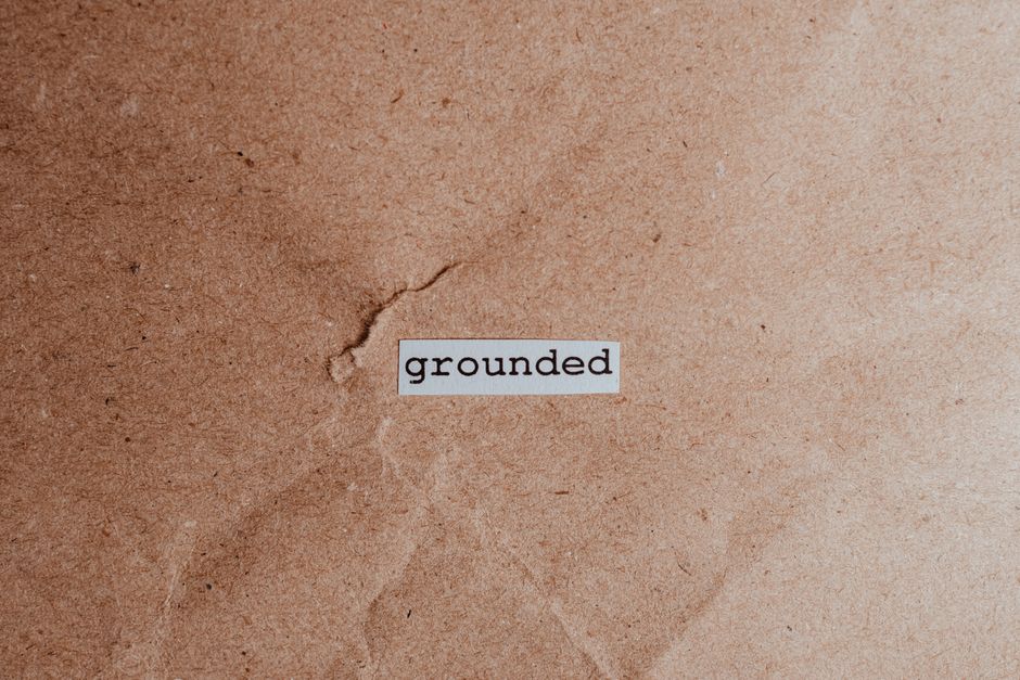 Textured brown surface with the word 'grounded', conveying stability and mindfulness.