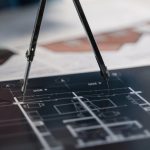 The 1955 Innovation Blueprint: Why Old Tech Still Drives Strategy A compass on architectural blueprints, showcasing planning and measurement details.