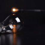 The 1955 Invention That Still Dictates Modern Operational Strategy Detailed shot of a reflective light bulb on a dark background, showcasing lighting and reflections.