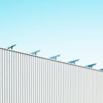 Corrugated steel building with solar panels under a clear blue sky, emphasizing sustainability.