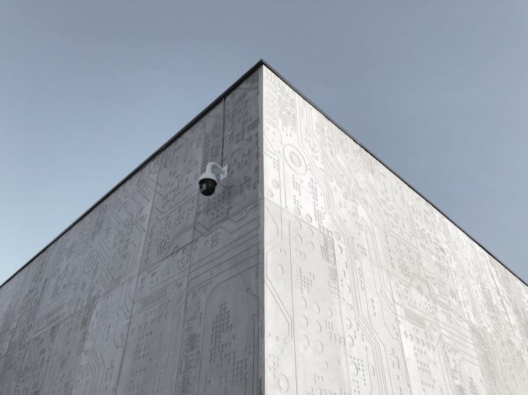 Elevated view of a futuristic building corner in Moscow, featuring circuit design patterns and a security camera.