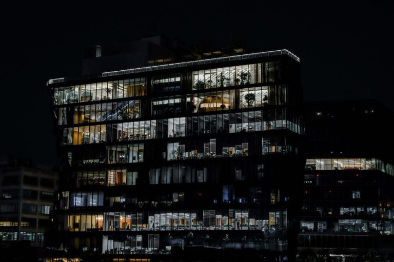 A captivating image of a contemporary office building illuminated against the night sky, showcasing urban architecture.