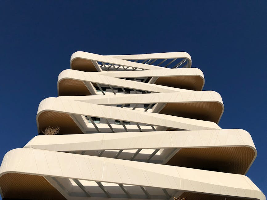 Striking low-angle view of a modern high-rise building in Madrid against a clear blue sky.