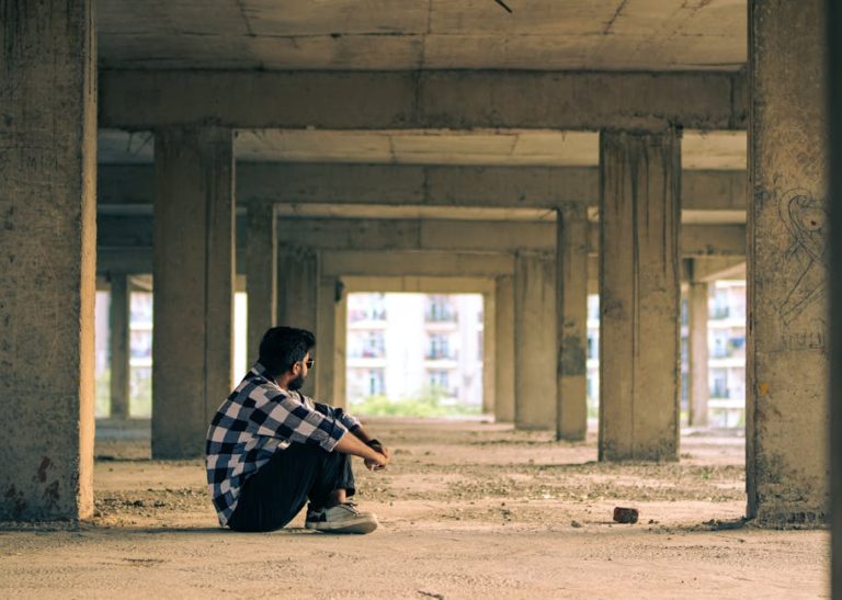 Young man sitting thoughtfully in an urban under-construction building in Noida, India.