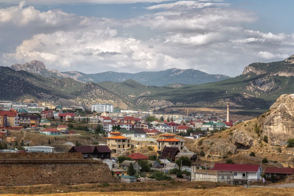 A breathtaking view of a town nestled in the Crimean mountains with a dramatic cloudy sky.