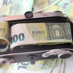 A vintage camera bundled with one hundred euro banknotes, symbolizing financial value.