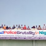 A demonstration against police brutality in Nigeria with people holding a large banner on a bridge.