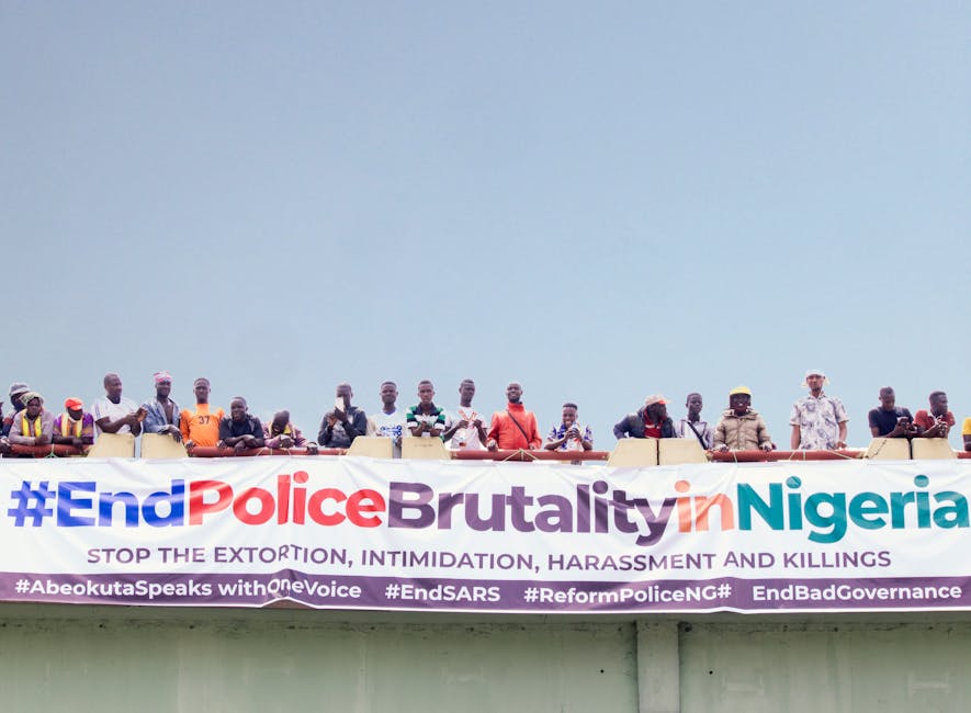 A demonstration against police brutality in Nigeria with people holding a large banner on a bridge.