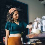 The Conscious Economy: Ethical Risks in Algorithmic Decision-Making A woman replenishing glass jars with grains in an eco-friendly store, promoting zero-waste shopping.