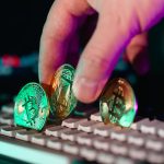 Close-up of cryptocurrency coins on a keyboard with a hand, symbolizing digital currency and finance technology.