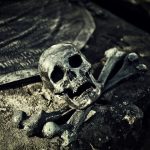 A haunting close-up of a skull and crossbones on an ancient tombstone in a spooky cemetery.