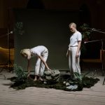 The Ecological Cost of Style: Strategic Shifts in Modern Fashion Two individuals in a creative indoor setup with plants and eco-friendly theme.