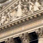 Ornate façade of the New York Stock Exchange featuring intricate stone sculptures during daylight.