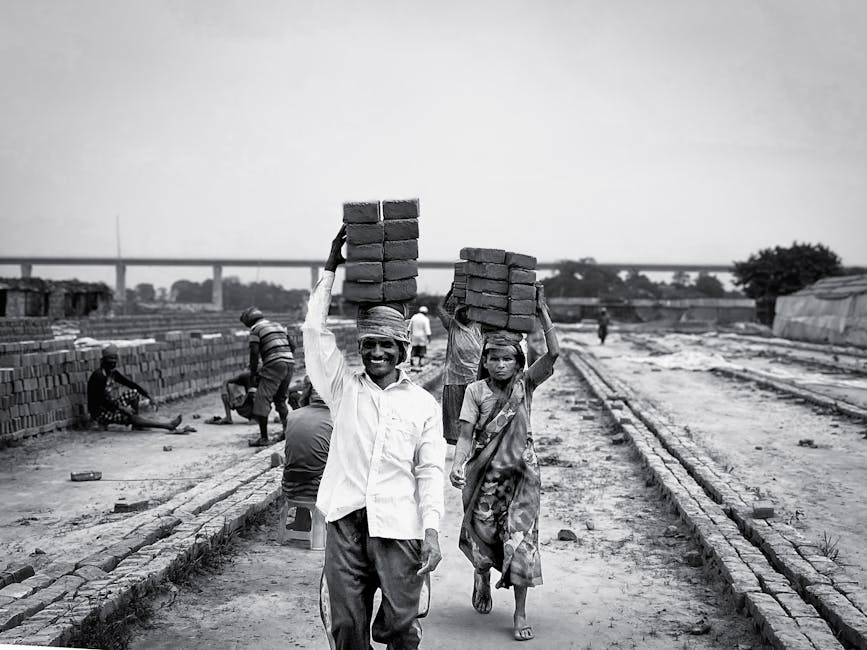 Black and white photo of laborers carrying bricks, depicting hard work and industry.