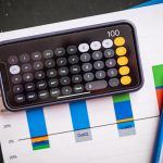 The Economic Calculus of Migration: A Strategic Framework for Leaders Mobile calculator on paper charts indicating financial analysis with colorful data visualization.