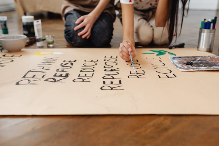 Hands painting on a poster with sustainable message during a school project.