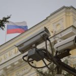 Close-up of surveillance cameras on a Russian building facade with flag.