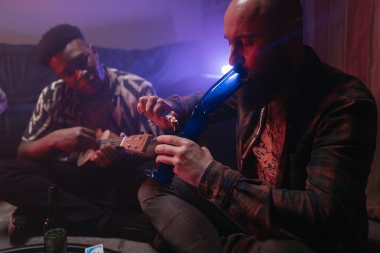 Two friends enjoying music and smoking indoors, capturing a relaxed atmosphere with a musical instrument and smoke.
