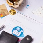 The Economics of Impulse: How Finance Shapes Consumer Behavior Close-up of financial documents, credit cards, coins, and a pen on a wooden desk.