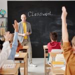 A teacher interacts with diverse students in a classroom, engaging them in active learning.