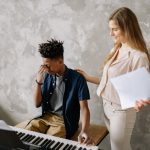 The Empathy Advantage: How Musical Resonance Drives High Performance A boy appears frustrated during a piano lesson with a supportive teacher.