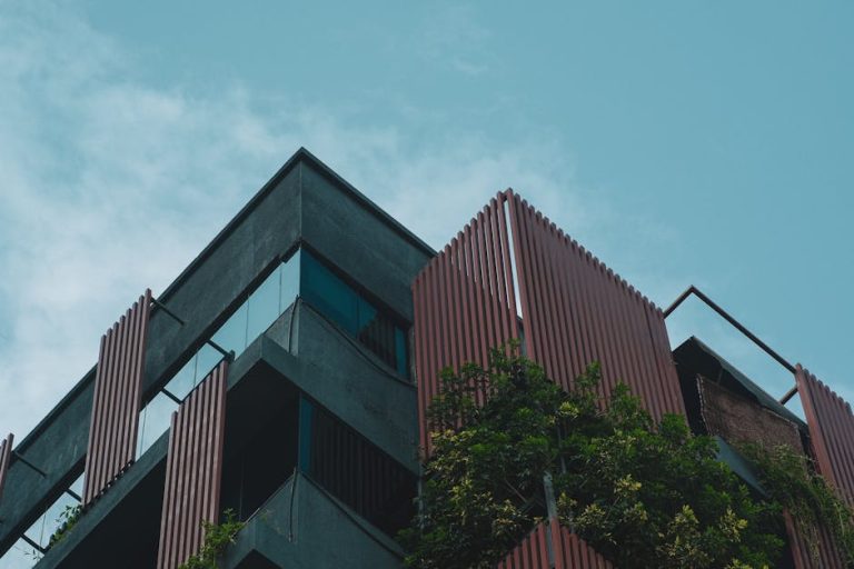 Angle view of a modern tropical building with vertical slats and greenery.