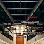 The Ethical Architecture of Language: Strategic Implications for Leaders An architectural interior in Berlin featuring suspended German words and phrases highlighting social themes.