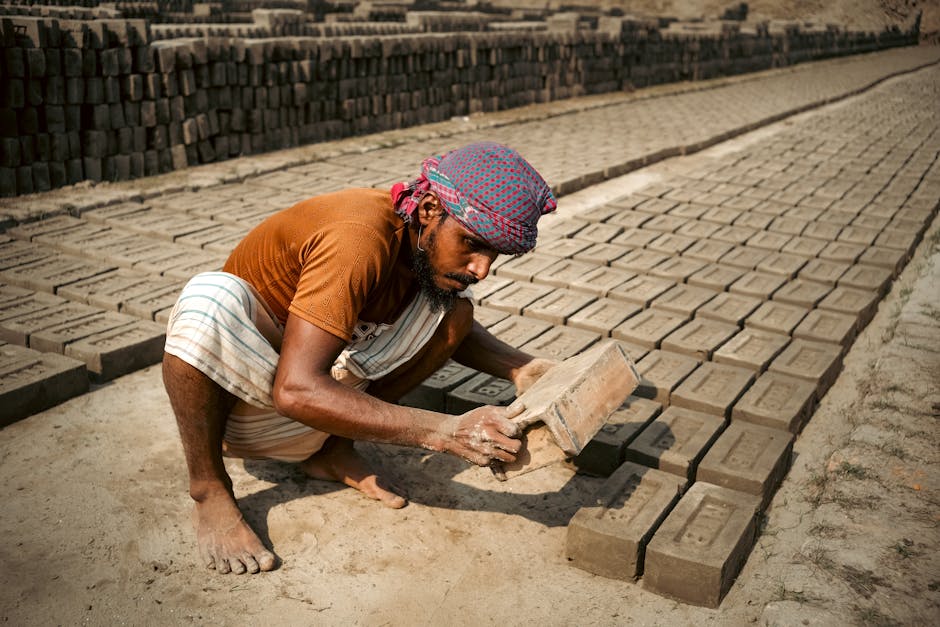 An artisan assembles bricks in a sunny outdoor kiln, showcasing traditional craftsmanship.