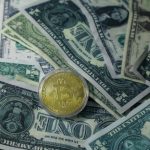 Close-up of Bitcoin cryptocurrency coin on a pile of US dollar banknotes, symbolizing finance and digital currency.