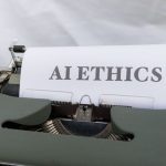 Close-up of vintage typewriter with 'AI ETHICS' typed on paper, emphasizing technology and responsibility.
